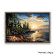 Framed canvas art print of a lakeside rustic cabin, aglow with campfire light against a soft sunset backdrop